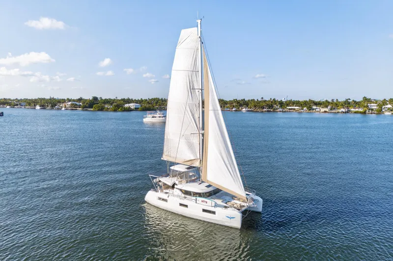 White Heron Yacht Photos Pics 2021 Lagoon 46 Owner's Version sailing on calm waters under a clear blue sky.
