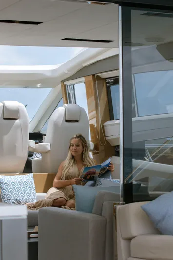  Yacht Photos Pics Woman relaxing on a 2016 Princess V72 yacht, reading a magazine in a luxurious interior.