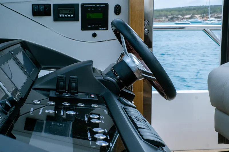  Yacht Photos Pics Steering wheel and controls of a 2016 Princess V72 yacht, overlooking the sea.
