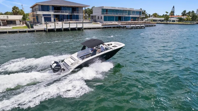  Yacht Photos Pics 2018 Sea Ray SDX 290 cruising on a sunny waterfront near modern homes.