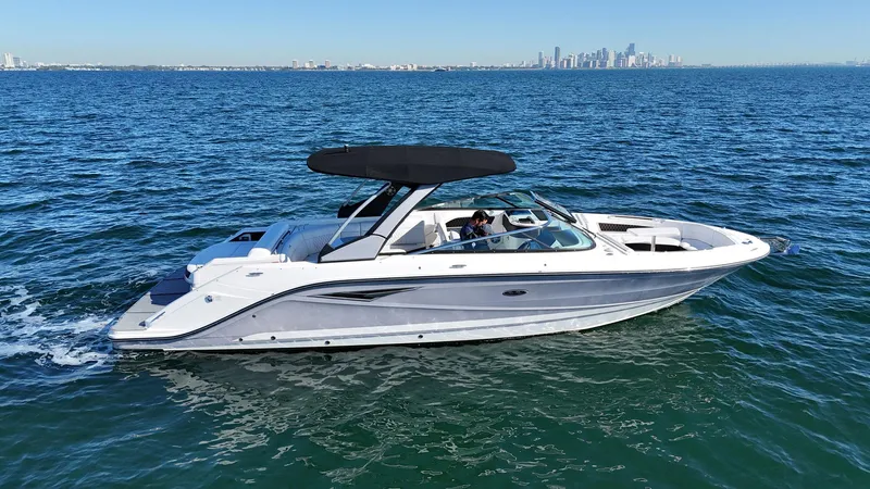  Yacht Photos Pics 2019 Sea Ray SLX 310 boat cruising on open water with city skyline in background.
