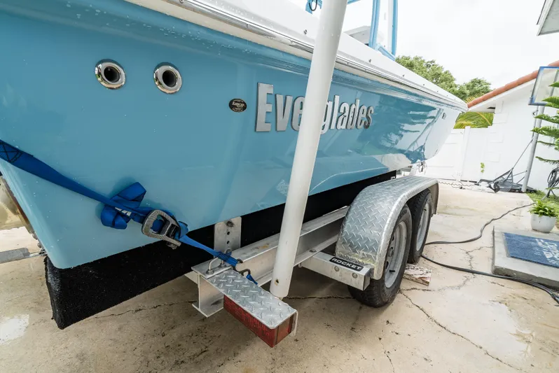 Yacht Photos Pics 2021 Everglades 243 Center Console boat on trailer, blue hull, secured with straps.
