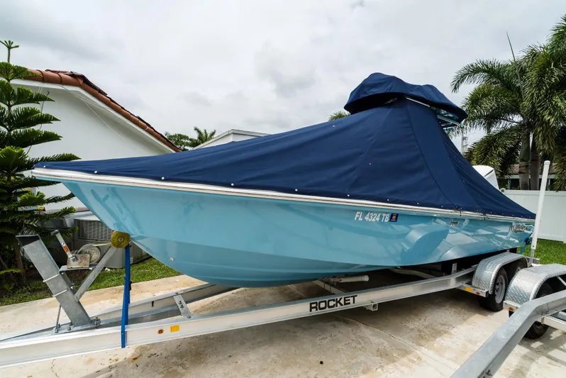  Yacht Photos Pics 2021 Everglades 243 Center Console boat on trailer, covered with blue tarp.