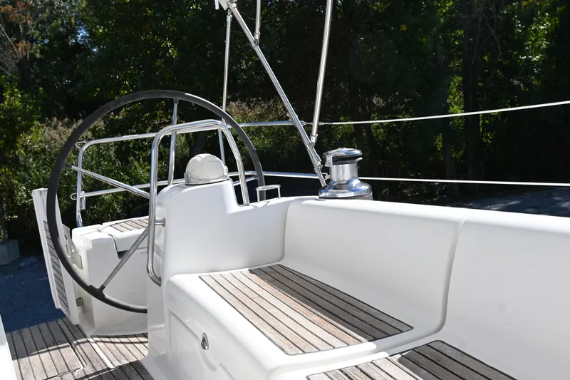Liberty Yacht Photos Pics 2011 Beneteau Oceanis 50 yacht cockpit with steering wheel and winch, surrounded by lush greenery.