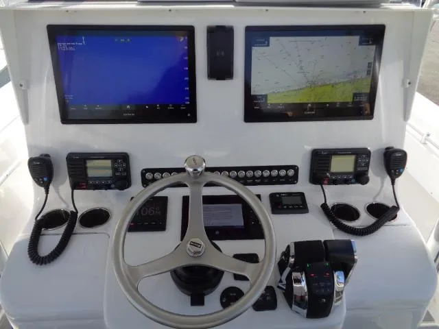 Yacht Photos Pics Control panel of 2022 Contender 32 ST boat with navigation screens and steering wheel.