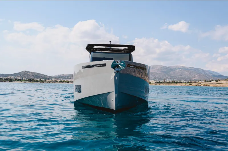  Yacht Photos Pics 2023 De Antonio Yachts D42 Open on serene blue water with mountainous backdrop.