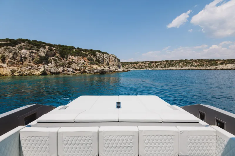  Yacht Photos Pics 2023 De Antonio Yachts D42 Open on serene blue waters near rocky coastline.