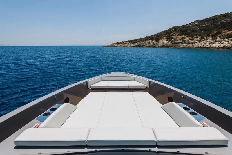  Yacht Photos Pics 2023 De Antonio Yachts D42 Open on serene blue waters near rocky coastline.