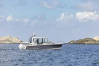 2026 Nimbus Commuter 8 boat cruising on a calm sea with rocky islands in the background.