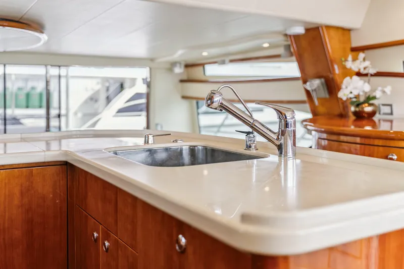 Day To Day Yacht Photos Pics Luxurious kitchen area on a 2008 Neptunus 62 Flybridge yacht with modern sink and wood cabinetry.