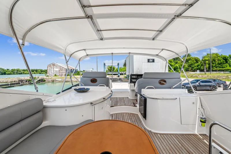 Day To Day Yacht Photos Pics 2008 Neptunus 62 Flybridge yacht interior with seating and helm, docked by a scenic waterfront.