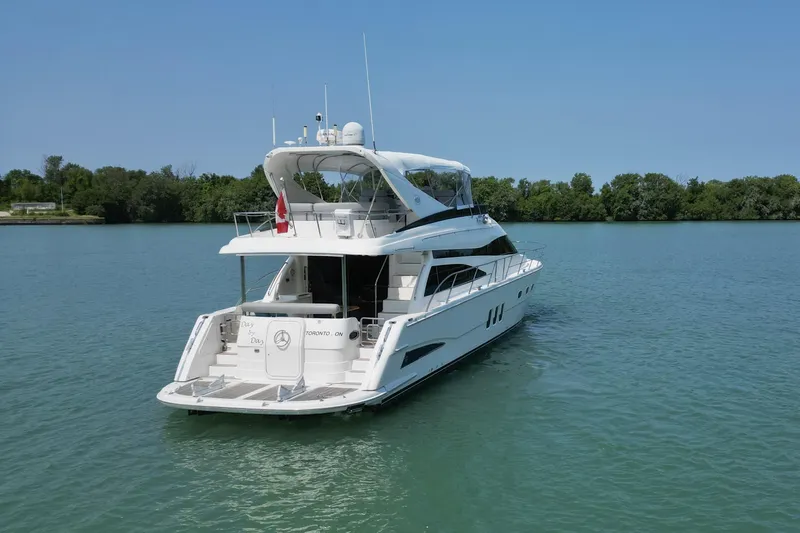 Day To Day Yacht Photos Pics 2008 Neptunus 62 Flybridge yacht on calm water, surrounded by trees.