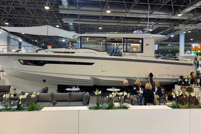  Yacht Photos Pics 2025 Nimbus C11 boat displayed at an indoor exhibition with people seated nearby.