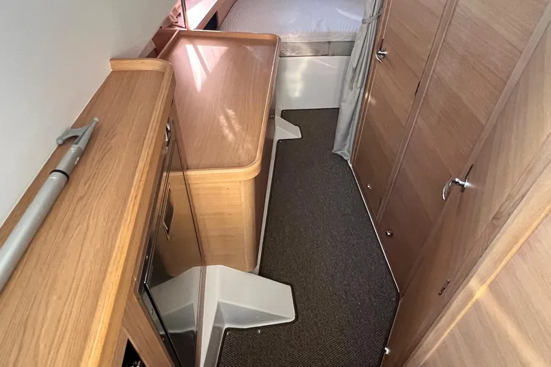  Yacht Photos Pics Interior of 2025 Nimbus C11 boat with wooden cabinetry and compact sleeping area.