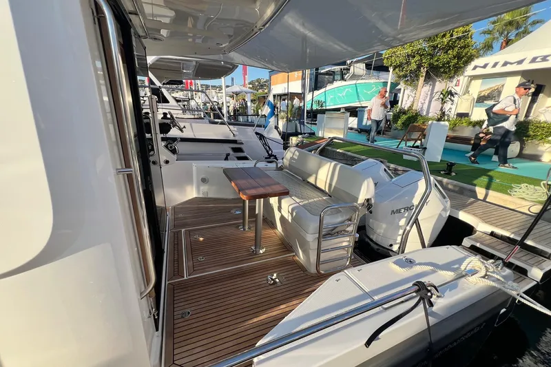  Yacht Photos Pics 2025 Nimbus C11 boat interior with seating, table, and Mercury engine at a marina.