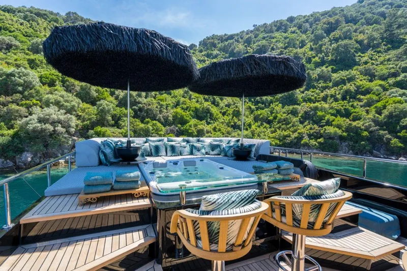 Queen Karina Yacht Photos Pics Luxurious Cheoy Lee 92 ft yacht deck with jacuzzi and seating, surrounded by lush greenery.