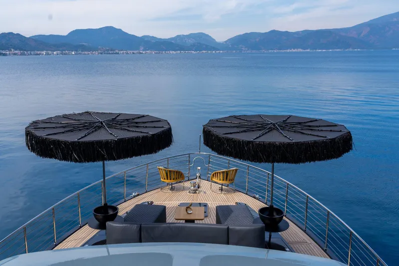 Queen Karina Yacht Photos Pics Luxurious Cheoy Lee 92 ft yacht deck with umbrellas, overlooking serene blue waters and distant mountains.