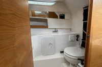Compact boat bathroom with toilet and sink, featuring wooden accents, in a 2019 Nimbus W 9.