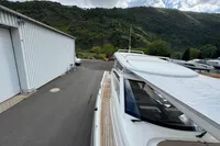 2019 Nimbus W 9 boat docked near a warehouse, surrounded by lush green hills.