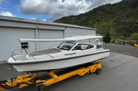 2019 Nimbus W 9 boat on trailer, parked near industrial building, cloudy sky background.