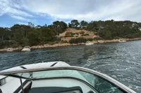 2019 Regal 26 FasDeck boat cruising near a scenic, tree-lined shoreline.