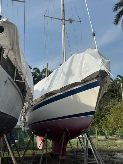 Challenger Yacht Photos Pics 1992 Hallberg-Rassy 45 sailboat on stands, covered, with trees in the background.