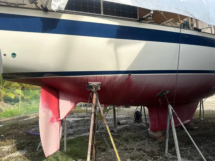 Challenger Yacht Photos Pics Hallberg-Rassy 45 sailboat from 1992 on stands, showing red hull and blue stripe.