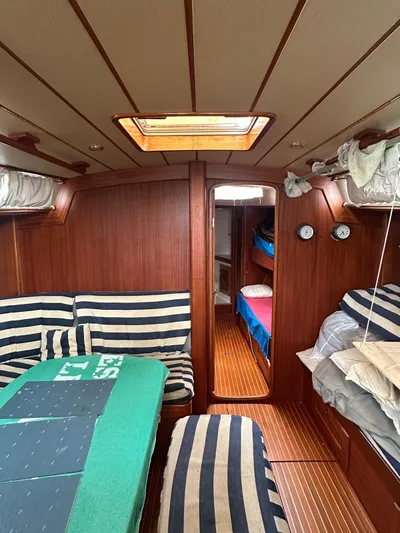 Challenger Yacht Photos Pics Interior of a 1992 Hallberg-Rassy 45 sailboat with striped seating and wooden paneling.