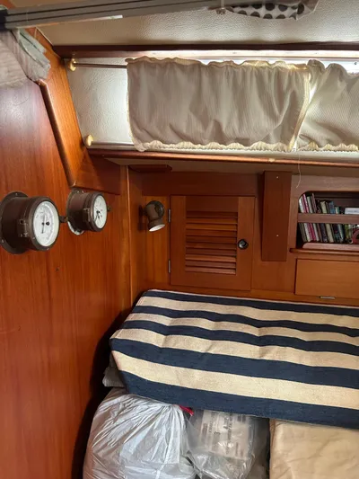 Challenger Yacht Photos Pics Interior cabin of 1992 Hallberg-Rassy 45 sailboat with striped bedding and wooden paneling.