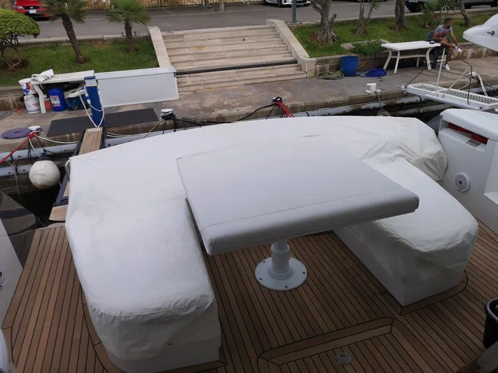  Yacht Photos Pics 2007 Pershing 62 yacht deck with covered seating and table, docked at marina.