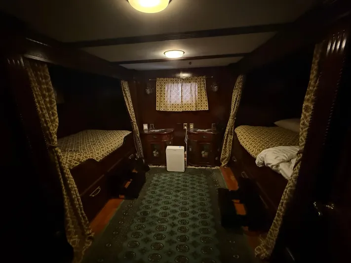  Yacht Photos Pics Cozy cabin interior with twin beds, patterned curtains, and soft lighting on a 2000 Pluckebaum Custom boat.