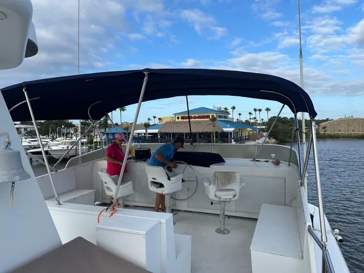  Yacht Photos Pics Two people on a 2000 Pluckebaum Custom boat with a blue canopy, dockside view.