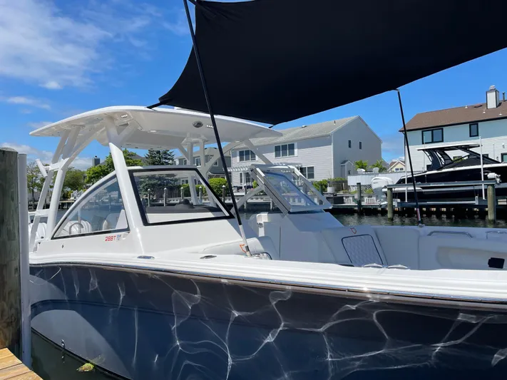  Yacht Photos Pics 2024 Sea Fox 288 Traveler boat docked with sunshade, waterfront homes in background.
