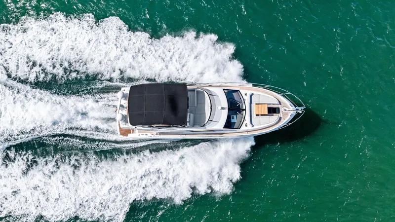 Almost Heaven Yacht Photos Pics Aerial view of 2021 Sunseeker Manhattan 52 yacht cruising on turquoise water.