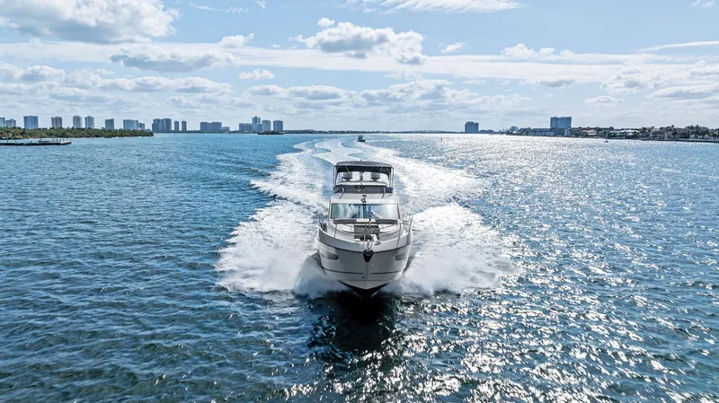 Almost Heaven Yacht Photos Pics 2021 Sunseeker Manhattan 52 yacht cruising on a sunny day, with city skyline in the background.