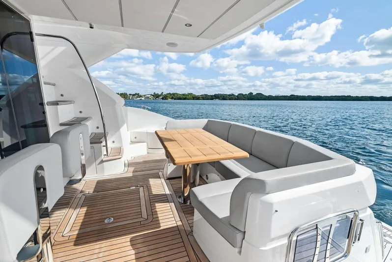 Almost Heaven Yacht Photos Pics Sunseeker Manhattan 52 yacht deck with seating and table, overlooking serene waters.