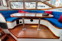 Luxurious interior of 1999 Custom Tasman 48 yacht with blue seating and wooden table.