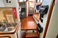 Interior of 1999 Custom Tasman 48 yacht with wooden flooring and compact kitchen area.
