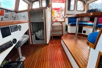 Interior of 1999 Custom Tasman 48 yacht with wooden flooring and blue seating.