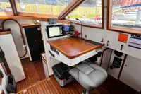 Interior of 1999 Custom Tasman 48 yacht with navigation station and wooden flooring.
