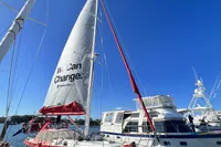 Sailboat "Tasman 48" docked, featuring a prominent sail with "We Can Change" text.