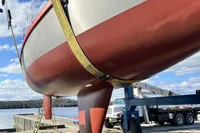 Custom Tasman 48 sailboat from 1999 being lifted at a dockside with a crane.
