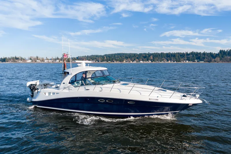  Yacht Photos Pics 2004 Sea Ray 390 Sundancer cruising on a scenic lake under a clear blue sky.