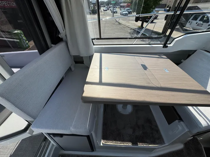  Yacht Photos Pics Interior of 2025 Jeanneau NC 795 Series 2, featuring a cozy dining area with a wooden table.