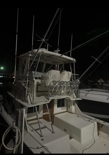  Yacht Photos Pics 1986 Blackfin 32 Flybridge boat docked at night, featuring fishing rods and covered seating.
