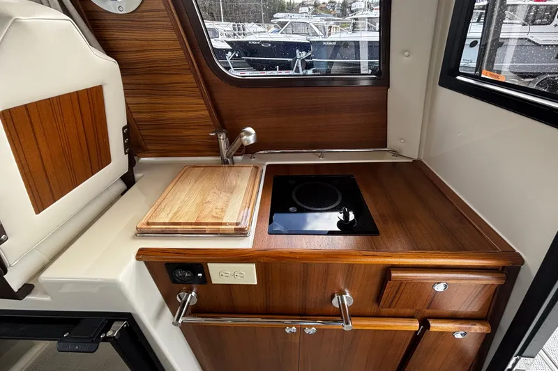  Yacht Photos Pics 2026 Ranger Tugs R-23 boat interior with wooden kitchenette and induction cooktop.