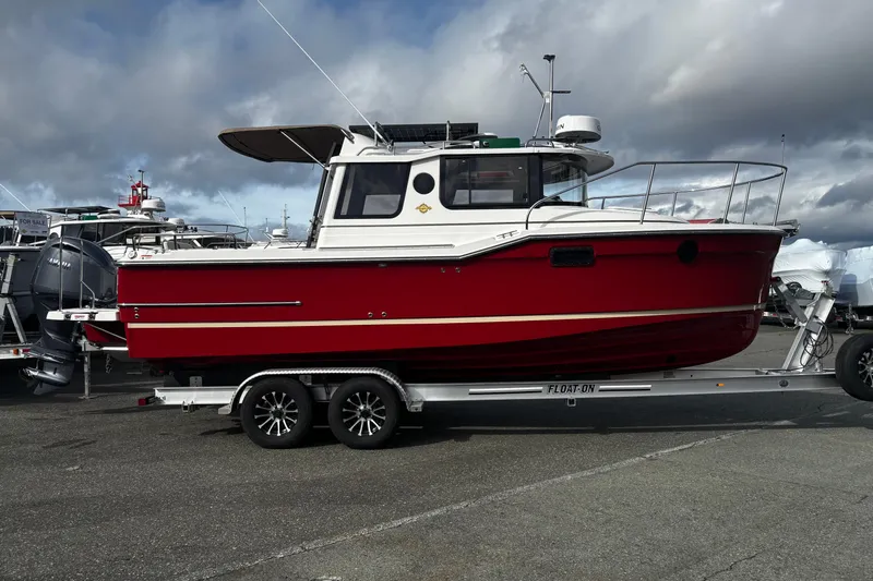  Yacht Photos Pics 2026 Ranger Tugs R-23 boat on trailer, red hull, parked outdoors under cloudy sky.