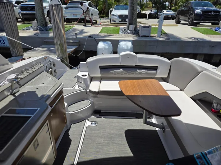 Love You More Yacht Photos Pics 2019 Four Winns H350 boat interior with seating and table, docked near luxury cars.