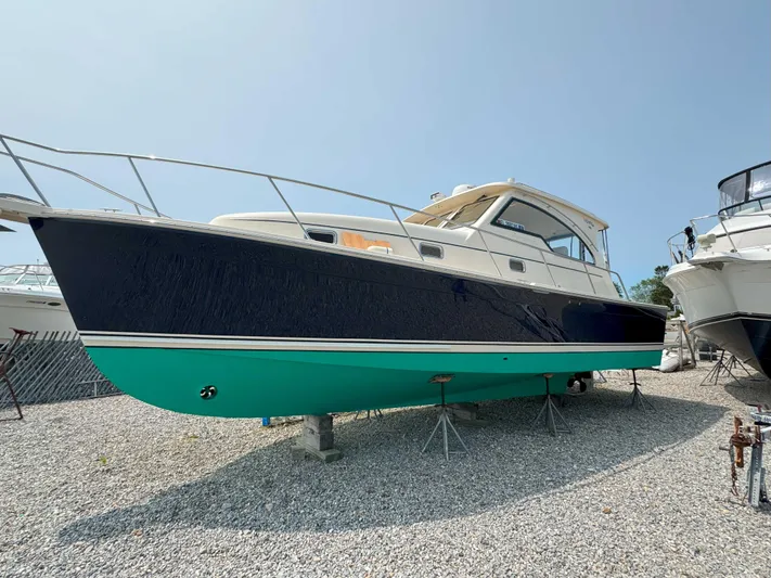 Fetch Yacht Photos Pics 2004 Mainship Pilot 34 boat on gravel, side view, blue and green hull.