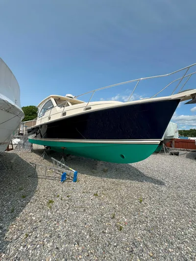 Fetch Yacht Photos Pics 2004 Mainship Pilot 34 boat on gravel, blue and green hull, docked outdoors.